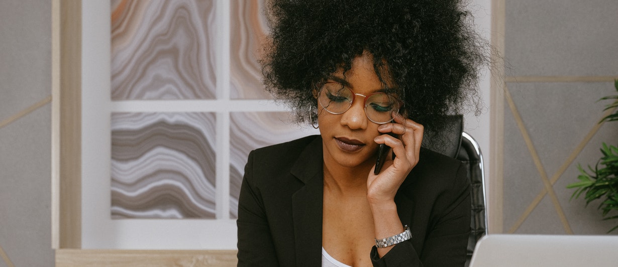 Mujer afroamericana de traje atendiendo al teléfono