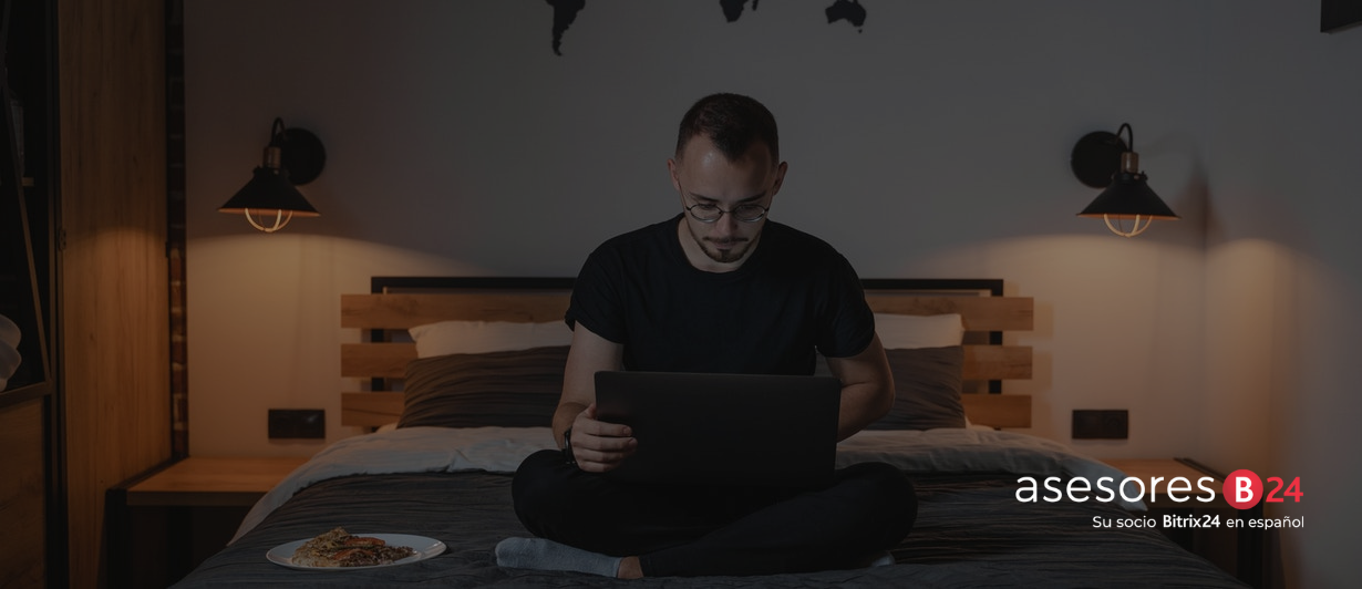 Hombre en su cama escribiendo en una laptop